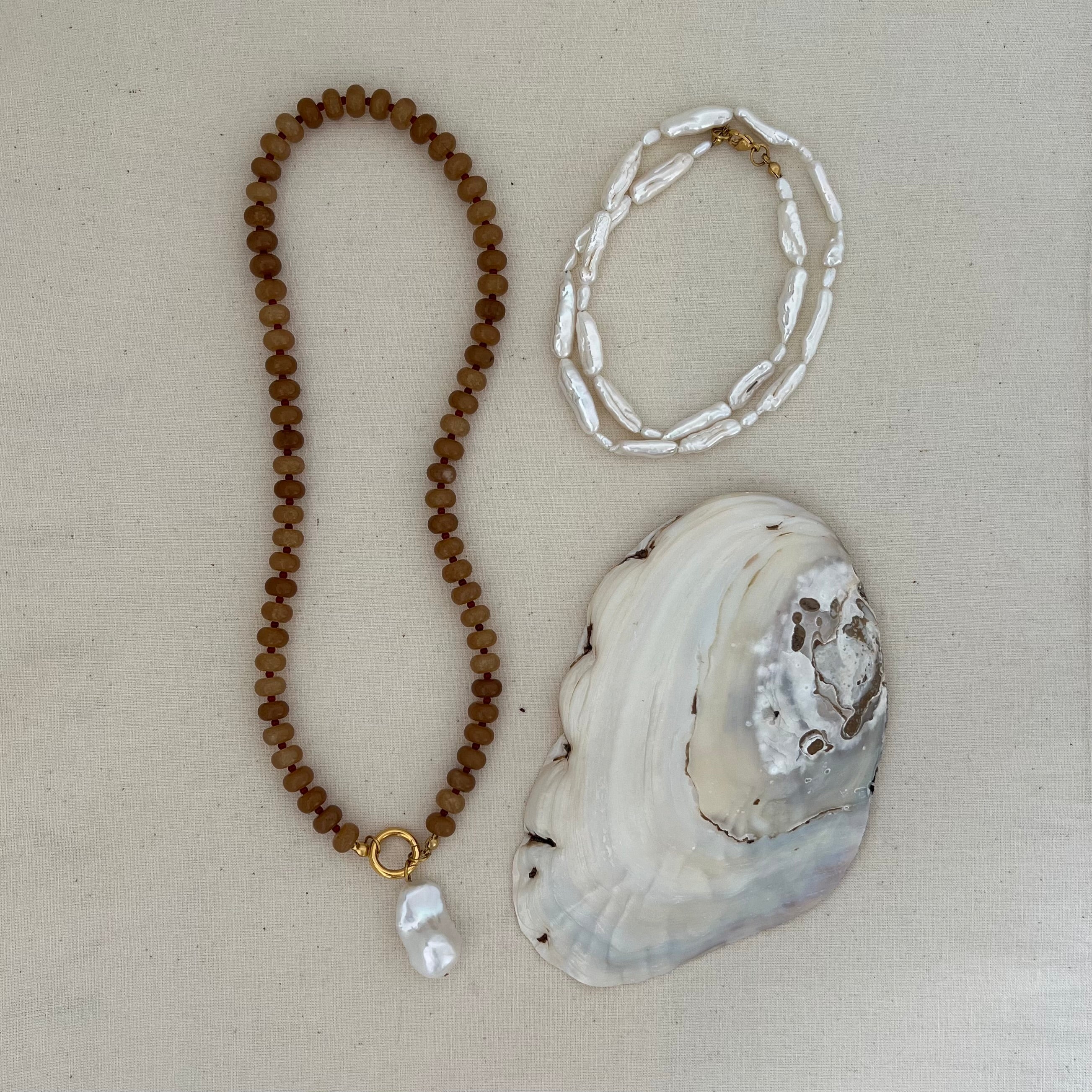 caramel jade beaded necklace and pearl necklace with gold clasps, styled with pearl and gold charms